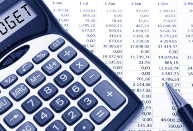 calculator with budget on screen and spreadsheets with numbers