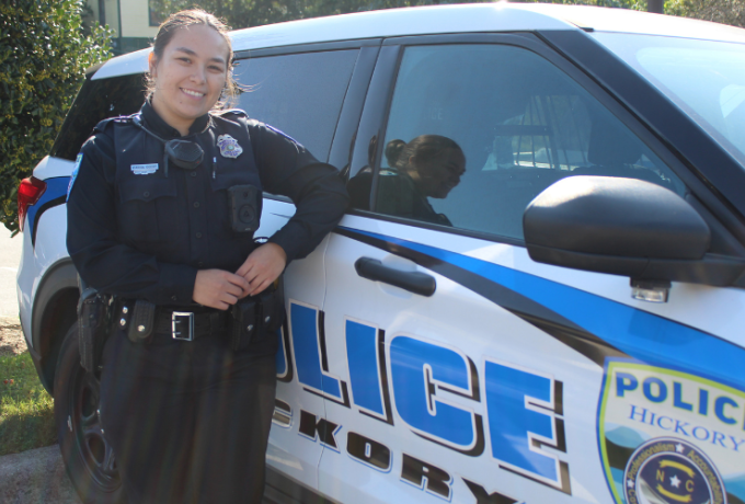 A young female Hickory police officer stands next to her cruiser.