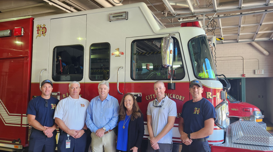fire department staff and equipment donors stand in front of a fire truck